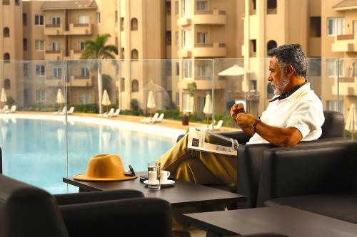 a man sitting in a chair next to a pool at Marom Port Said Resort & Beach in Port Said