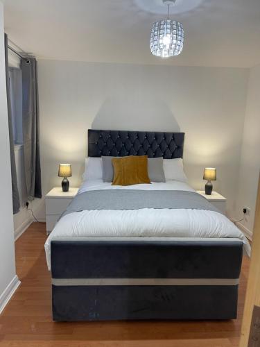 een slaapkamer met een groot bed met 2 nachtkastjes bij Entire 2 bedroom Beautiful newly furnished flat in Glasgow