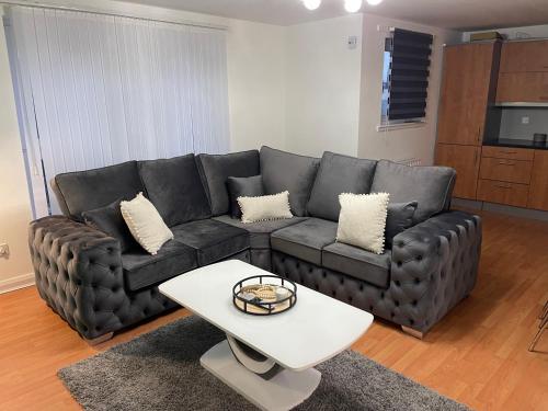 a living room with a black couch and a white table at Entire 2 bedroom Beautiful newly furnished flat in Glasgow
