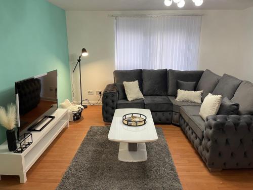 een woonkamer met een zwarte bank en een tafel bij Entire 2 bedroom Beautiful newly furnished flat in Glasgow