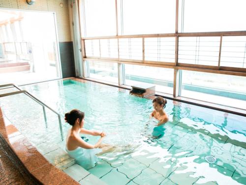 a woman and a child playing in a swimming pool at Kyukamura Irago in Tahara