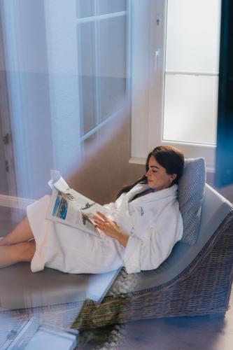 a woman laying on a chair reading a magazine at Kurhotel Drei Birken in Bad Rothenfelde