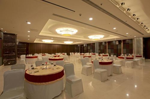 a banquet hall with white tables and white chairs at Goutham Grand Hotel in Tenāli