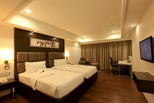 a hotel room with two beds and a flat screen tv at Goutham Grand Hotel in Tenāli