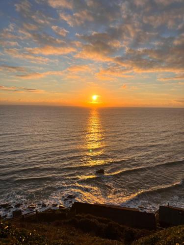 a sunset over the ocean with the sun setting at Sunset sea view chalet with hot tub in Torpoint