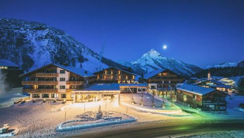 a lodge in the mountains at night with snow at Wellnesshotel Warther Hof in Warth am Arlberg