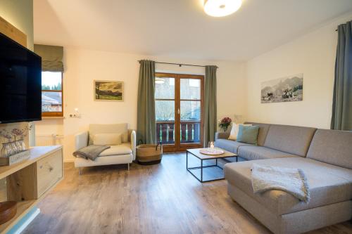 uma sala de estar com um sofá e uma televisão em Ferienwohnung Alpentraum - Wildblume em Fischen