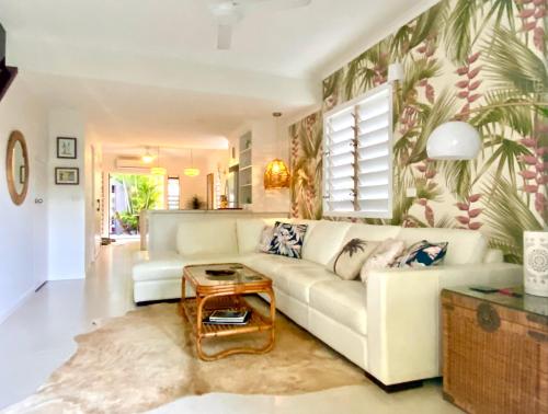a living room with a white couch and a table at Pandanus Place - with Bicycles in Port Douglas