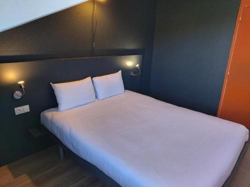 a large white bed with two pillows in a room at Ibis Budget Agen in Le Passage