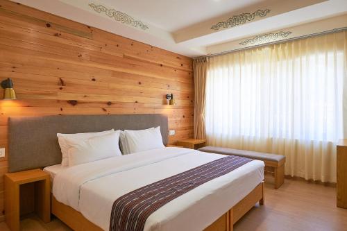 a bedroom with a large bed and a wooden wall at The Willows Hotel, Bhutan in Thimphu