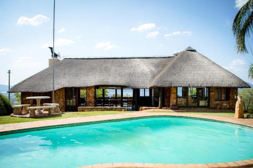 a hut with a swimming pool in front of it at Rock House at Benlize in Hartbeespoort