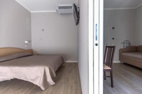 a bedroom with a bed and a chair and a couch at Hotel Susy in Rimini