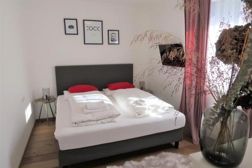 una camera da letto con un letto con lenzuola bianche e cuscini rossi di Mountain-Apart Simonhof a Maria Alm am Steinernen Meer
