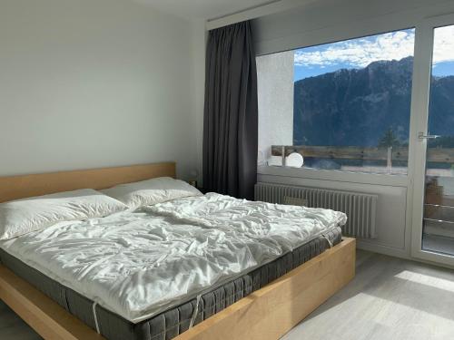 uma cama num quarto com uma grande janela em Roc d'Orsay C15 em Leysin