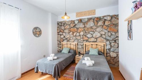 two beds in a room with a stone wall at Villa el Cerrillo Málaga - Churriana by Ruralidays in Málaga