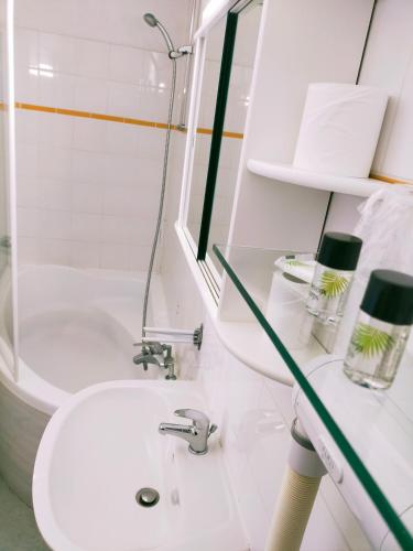 a white bathroom with a sink and a tub at Hôtel Restaurant l’Éolienne in Rouxmesnil-Bouteilles