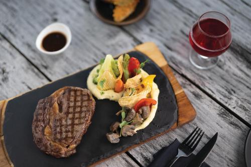 a black plate with a sandwich and bread and a glass of wine at VARU by Atmosphere - Premium All Inclusive with Free Transfers in North Male Atoll