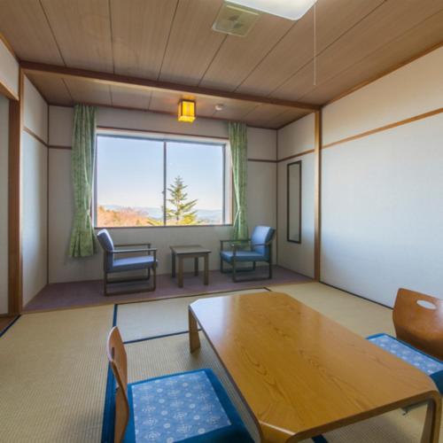 a room with a table and chairs and a large window at Kyukamura Chausuyama-Kogen in Toyone