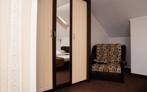 a mirror in a room with a chair and a bed at Pensiunea Lido Moisei in Moisei