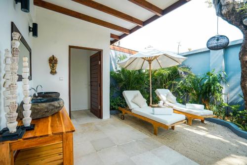 a patio with a tub and chairs and an umbrella at Pondok Santi Estate in Gili Trawangan
