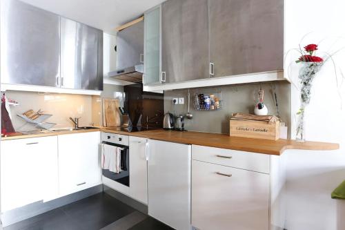 a kitchen with white cabinets and a wooden counter top at Grand studio plein centre de Chamonix in Chamonix-Mont-Blanc