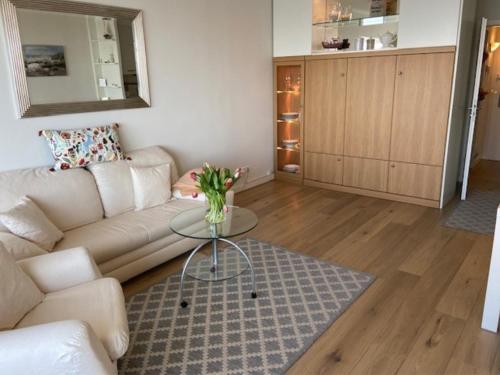 a living room with a couch and a glass table at Top - Seaside Appartement mit Meerblick in Timmendorfer Strand