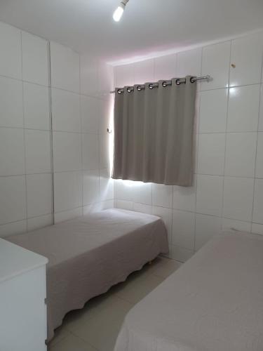 Cette chambre blanche comprend 2 lits et un rideau. dans l'établissement Apartamento em Camboinha, à João Pessoa