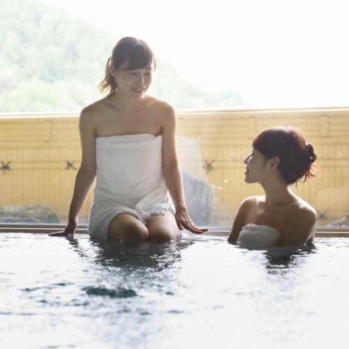 two women sitting in the water in a bathtub at Kyukamura Ohmi-Hachiman in Omihachiman