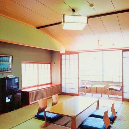 a living room with a table and chairs and a tv at Kyukamura Ohmi-Hachiman in Omihachiman