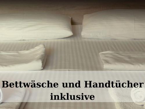 a bed with white sheets and pillows with the wordsustainable and habitual inclusive at Top - Seaside Appartement mit Meerblick in Timmendorfer Strand