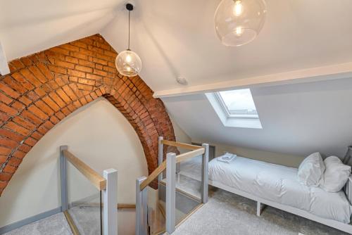 Pokój na poddaszu z ceglaną ścianą i łóżkiem w obiekcie Guest Homes - Barton Road House w mieście Hereford