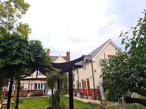 a house with a black pergola in a yard at Peaceful self contained Studio in lovely garden. in Hinckley