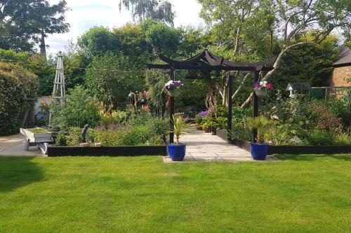 a garden with a gazebo and some plants at Peaceful self contained Studio in lovely garden. in Hinckley