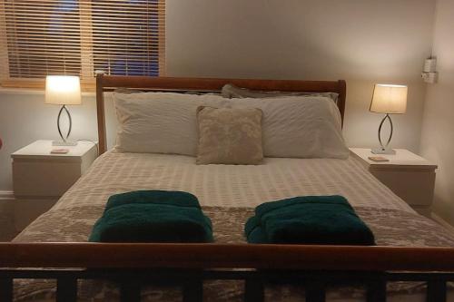 a bed with two green towels on it with two lamps at Peaceful self contained Studio in lovely garden. in Hinckley