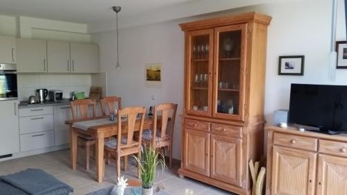 cocina con mesa y sillas y TV en Ferienwohnung A2 im Landhaus am Haff, en Stolpe auf Usedom