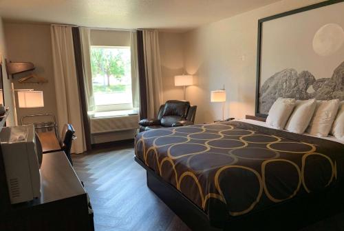 a hotel room with a bed and a chair and a window at Super 8 by Wyndham Greeley in Greeley