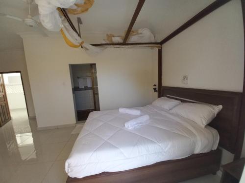 a bedroom with a large bed with white sheets at Maranda Deluxe Double Seaview room - B&B with pool. in Ukunda