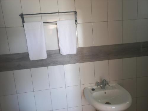 a white bathroom with a sink and two towels at Maranda Deluxe Double Seaview room - B&B with pool. in Ukunda