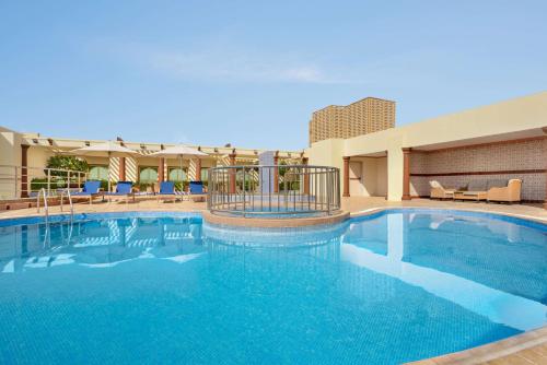 uma grande piscina com água azul num hotel em Wyndham Garden Dammam em Dammam