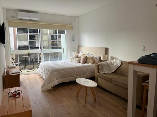 een slaapkamer met een bed, een bank en een tafel bij Refugio cómodo y luminoso. Excelente ubicación. in Buenos Aires
