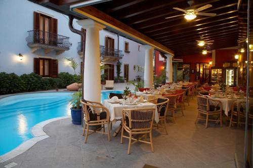 un restaurante con mesas y sillas junto a una piscina en Arciduca Grand Hotel en Lipari