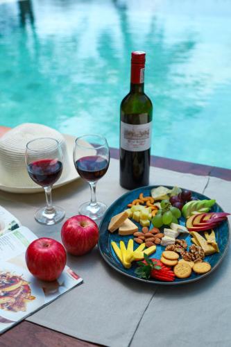 a table with a plate of food and a bottle of wine at River Arc Bolgoda Villa in Panadura