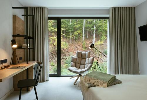 a bedroom with a bed and a desk and a chair at Hotel VierJahreszeiten am Seilersee in Iserlohn