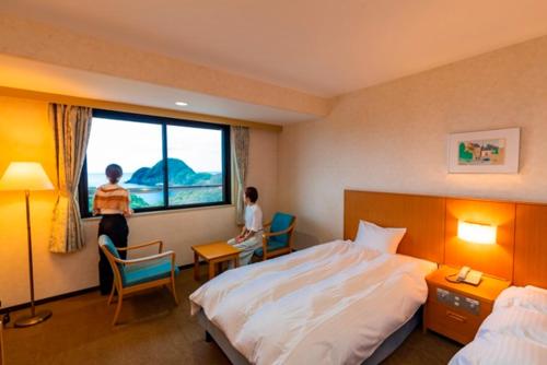um quarto de hotel com uma cama e uma janela em Kyukamura Takeno-Kaigan em Toyooka