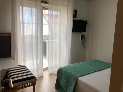 a bedroom with a bed and a window with white curtains at king's tower by Férias em Figueira in Figueira da Foz