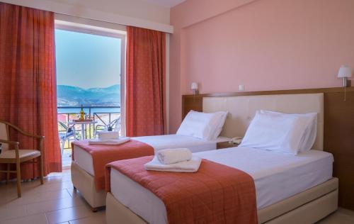 una camera d'albergo con due letti e una grande finestra di Palatino Hotel a Lixouri