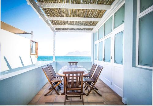 stół i krzesła na balkonie z widokiem na ocean w obiekcie Baytree Beach House w mieście Kalk Bay