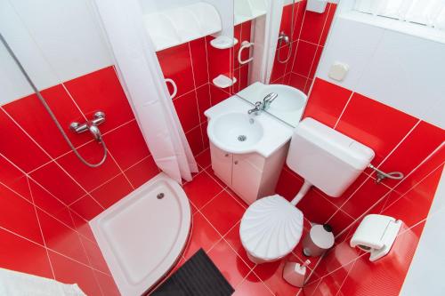 - une salle de bains rouge et blanche avec toilettes et lavabo dans l'établissement Apartment Sokol, à Batalaži