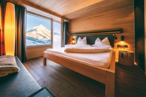 a bedroom with a bed with a view of a mountain at Wellnesshotel Warther Hof in Warth am Arlberg