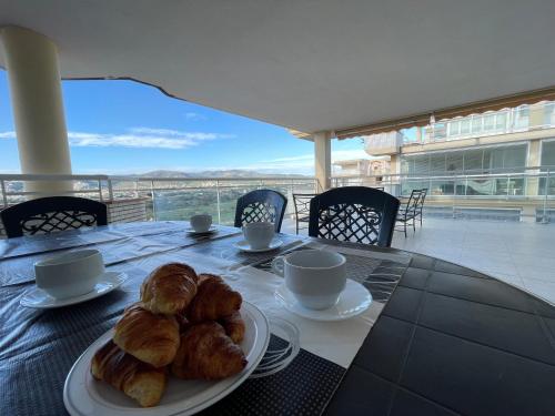 una mesa con un plato de cruasanes y tazas de café en Alpen1 Argenta/Caleta en Peñíscola